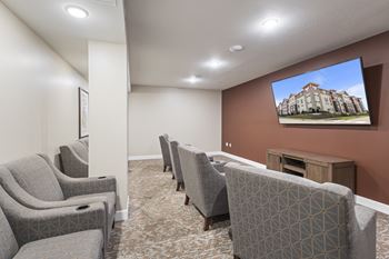 A community room with couches and chairs and a tv on the wall